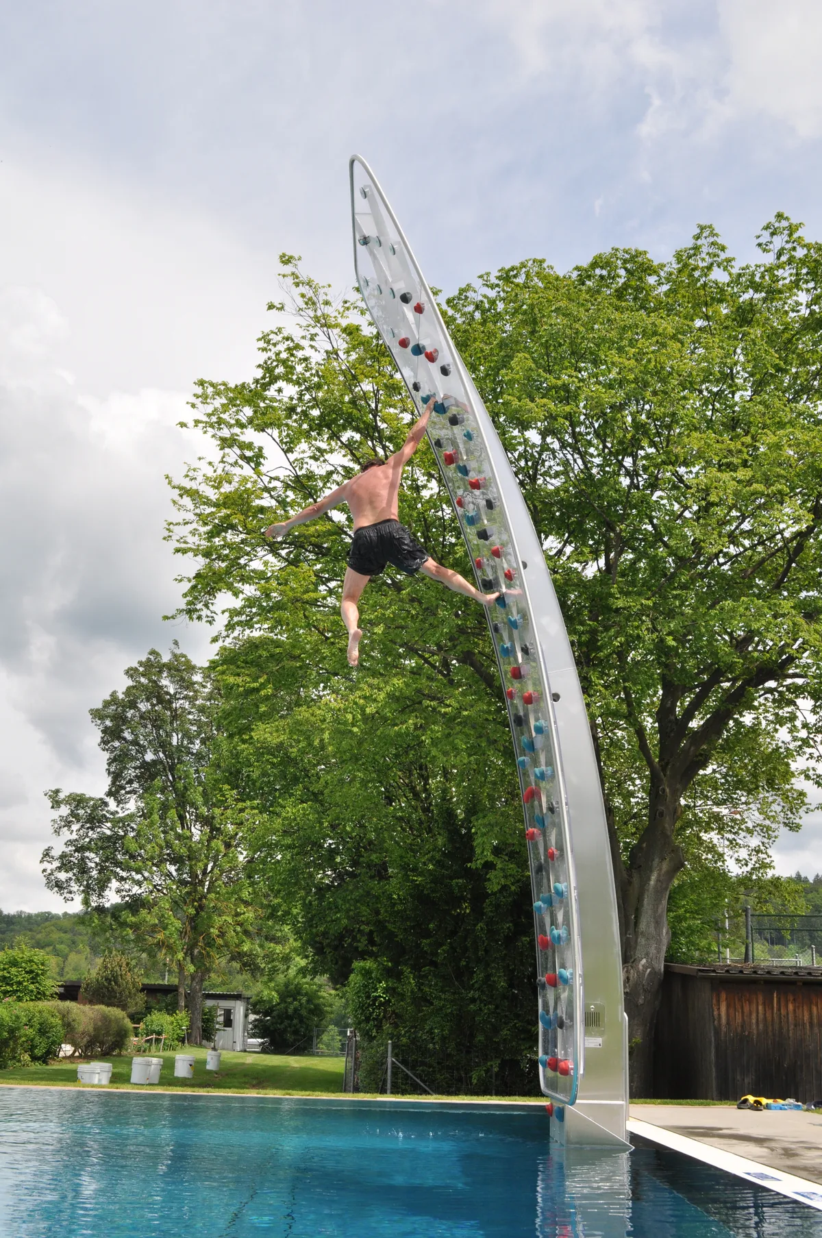 Ein Mann springt von einer Kletterwand ins Wasser.